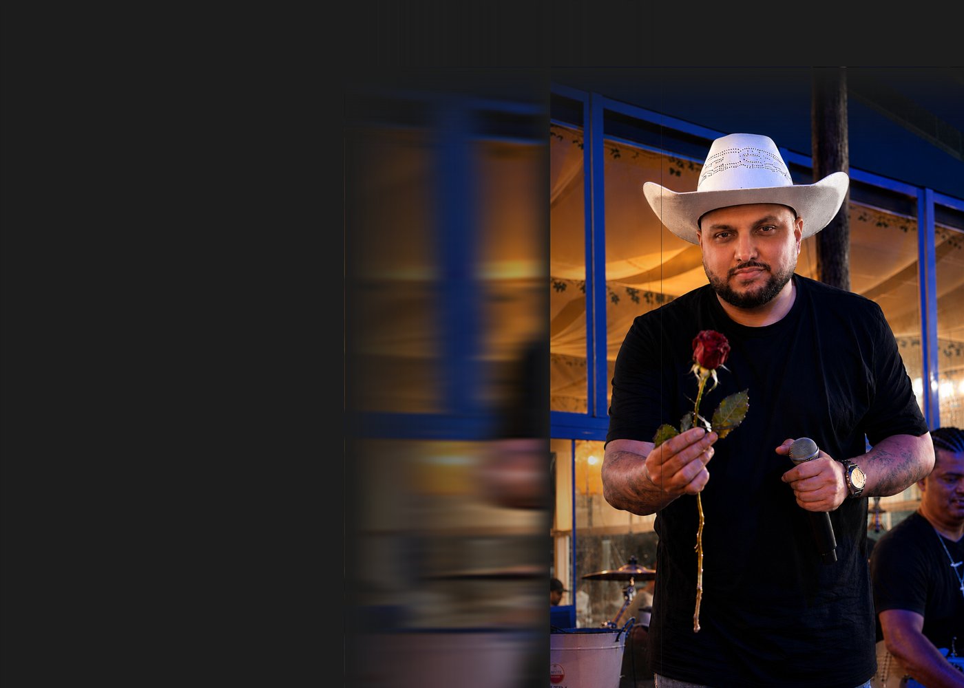 Cantor do Boteco do Romeo no palco, com uma rosa em uma das mãos e o microfone na outra
