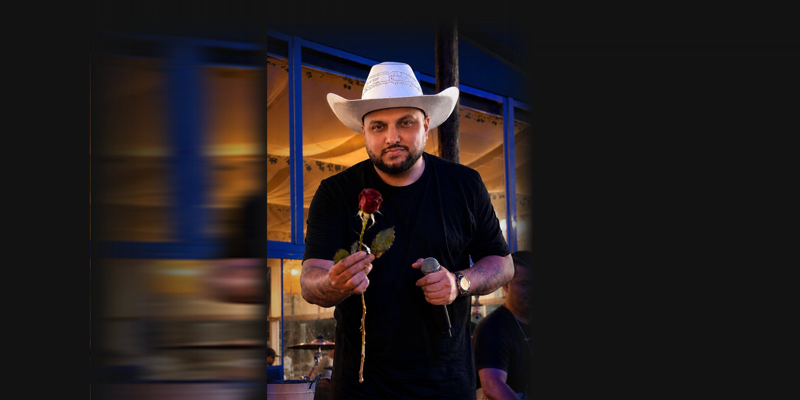 Boteco do Romeo no palco, com uma rosa em uma das mãos e o microfone na outra